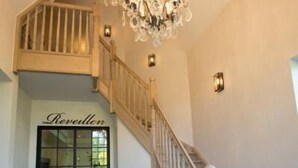 Una gran escalera con candelabro, barandal de madera y una puerta con la leyenda 'Revolution'.