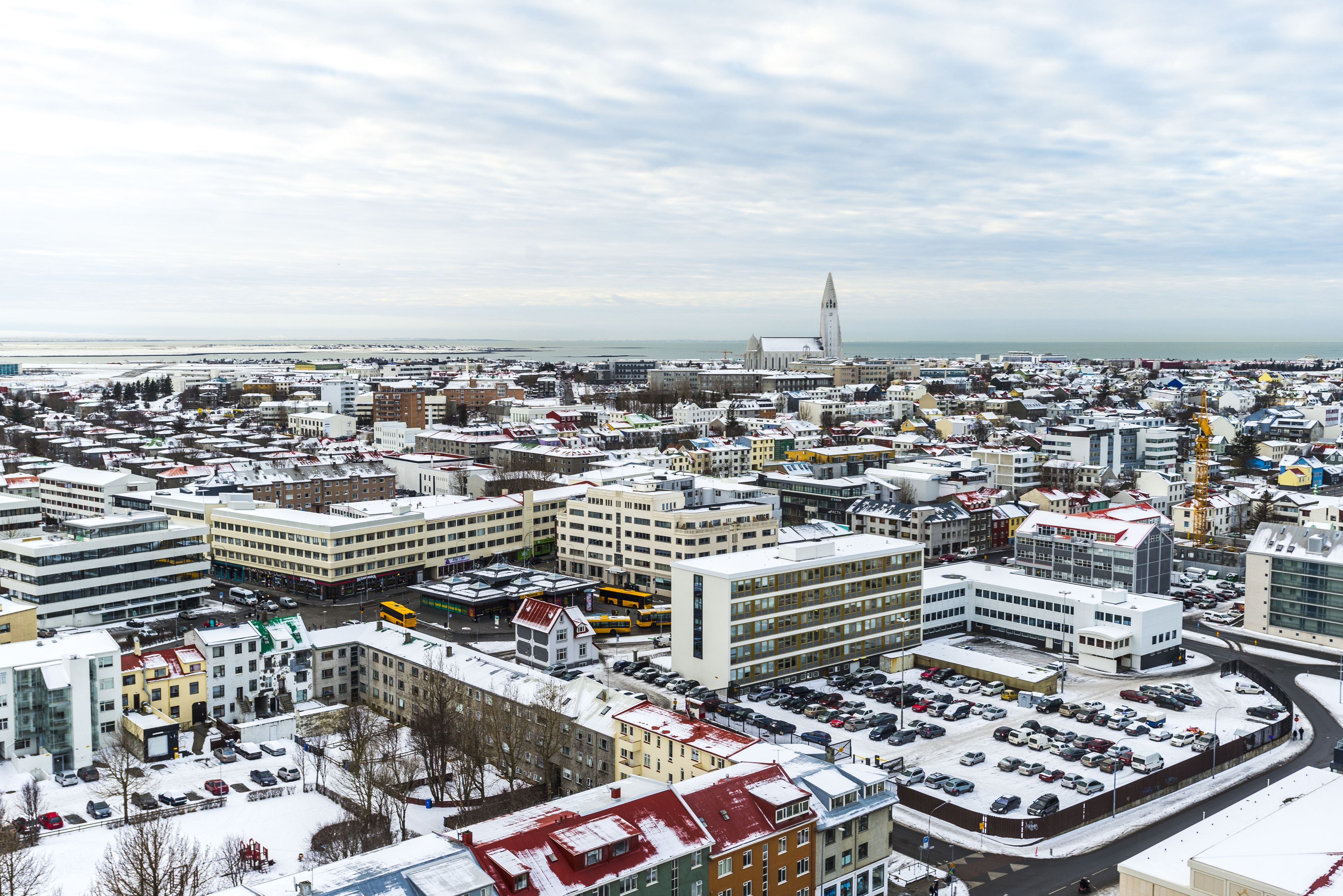 Een stadsgezicht met een combinatie van moderne en oudere gebouwen, een opvallende toren en een met sneeuw bedekte grond.