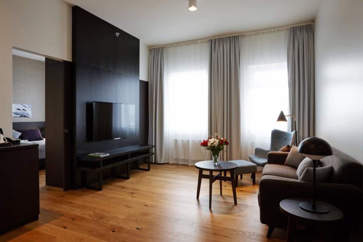 En moderne stue med et fladskærms-tv, en sofa, et sofabord med blomster og en lampe.