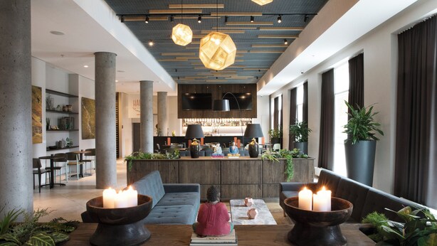 Un vestíbulo moderno con una zona de estar central, una recepción y un bar.