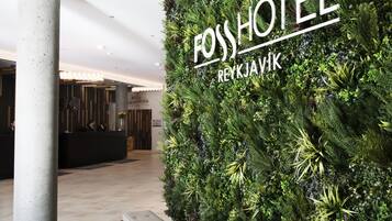 A reception area with a vertical garden wall, a reception desk, and a pillar.