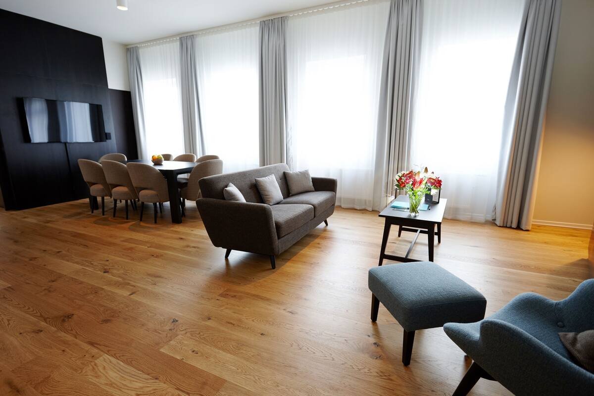 En moderne stue med sofa, stole, sofabord og et fjernsyn monteret på væggen.