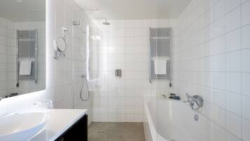 A modern bathroom with a large white bathtub, a double sink, and a glass-enclosed shower area.