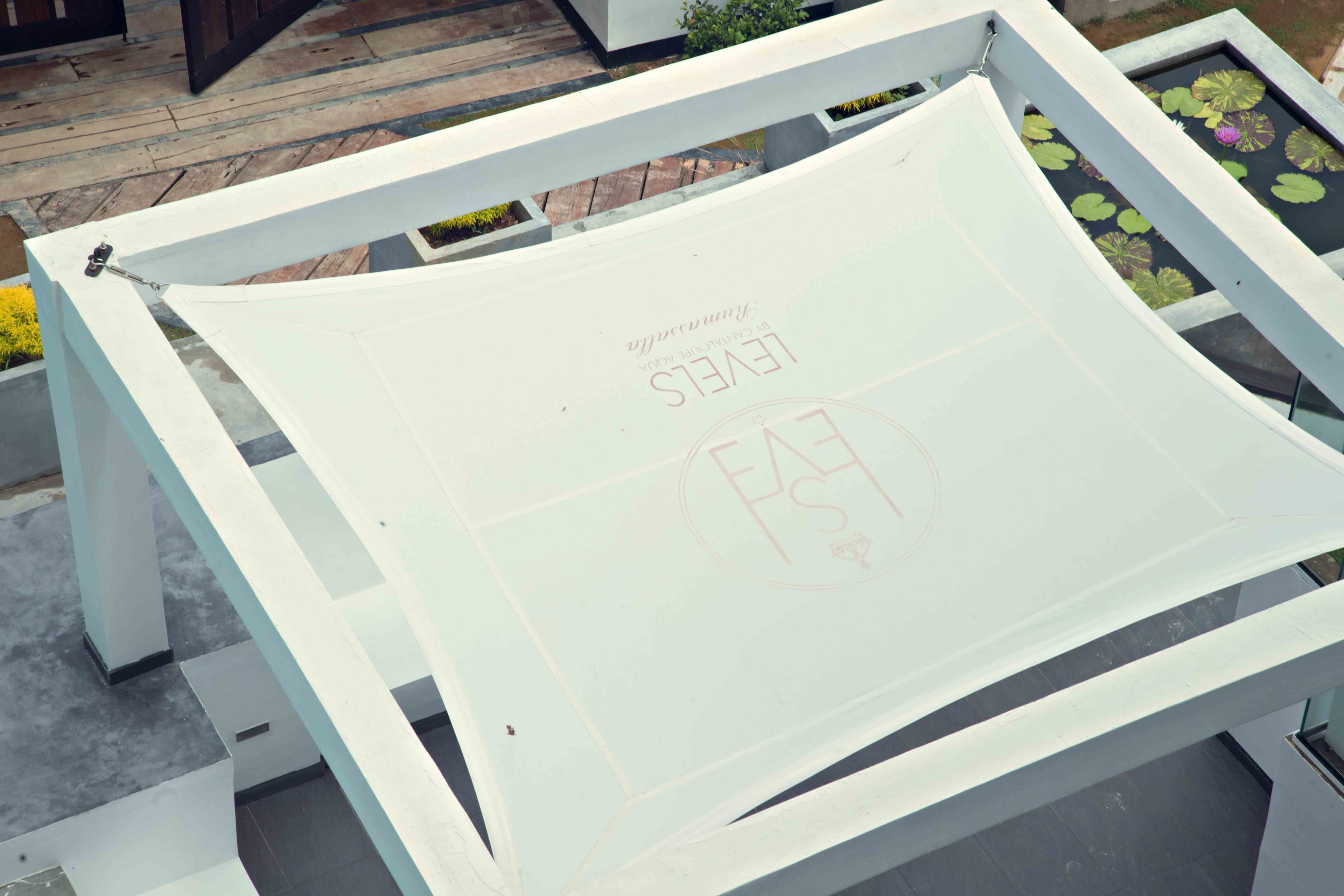A white outdoor seating area with a table and chairs, surrounded by a white railing.