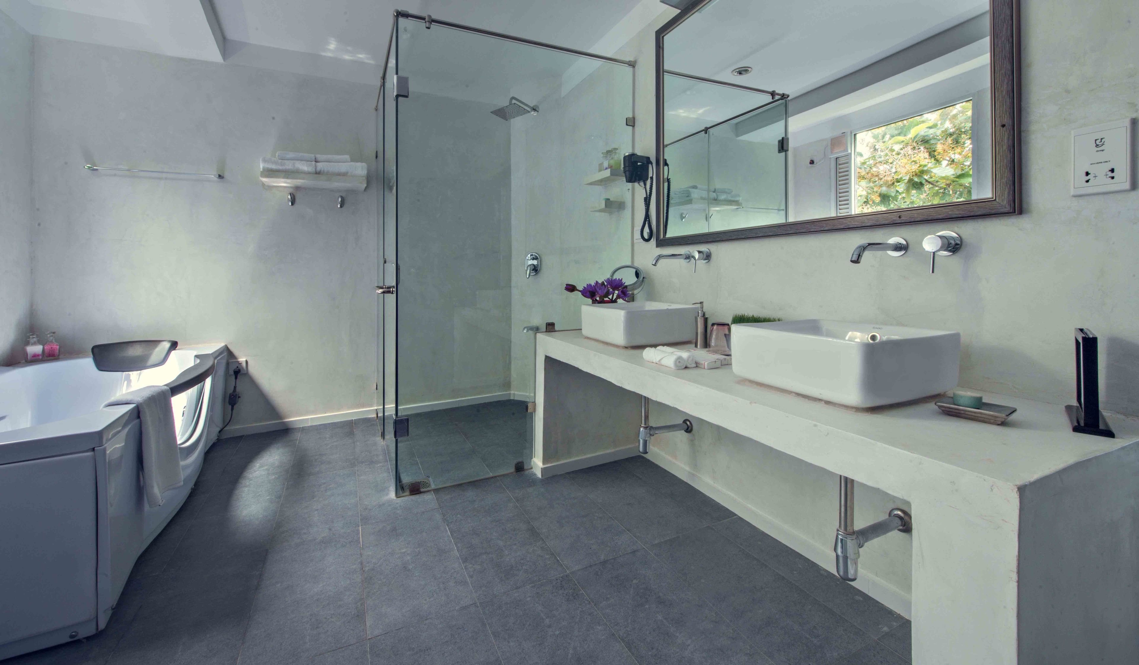 A modern bathroom with a glass-enclosed shower, a large mirror, and a dual sink vanity.