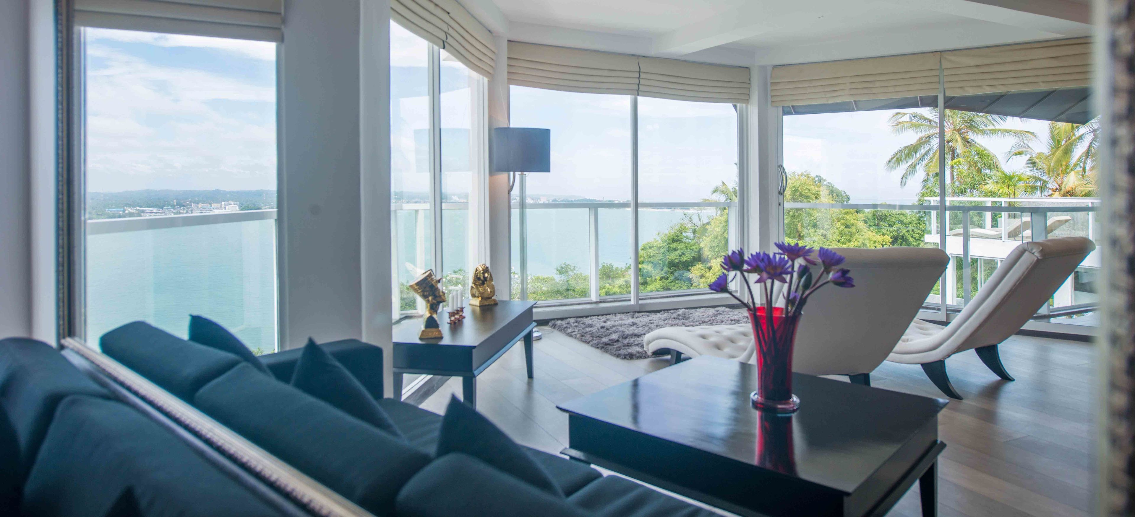 Un salón moderno con vistas al mar, un sofá, una mesa con un jarrón de flores y una silla.