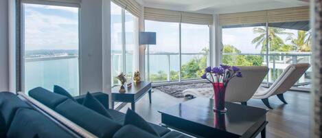Un salón moderno con vistas al mar, un sofá, una mesa con un jarrón de flores y una silla.
