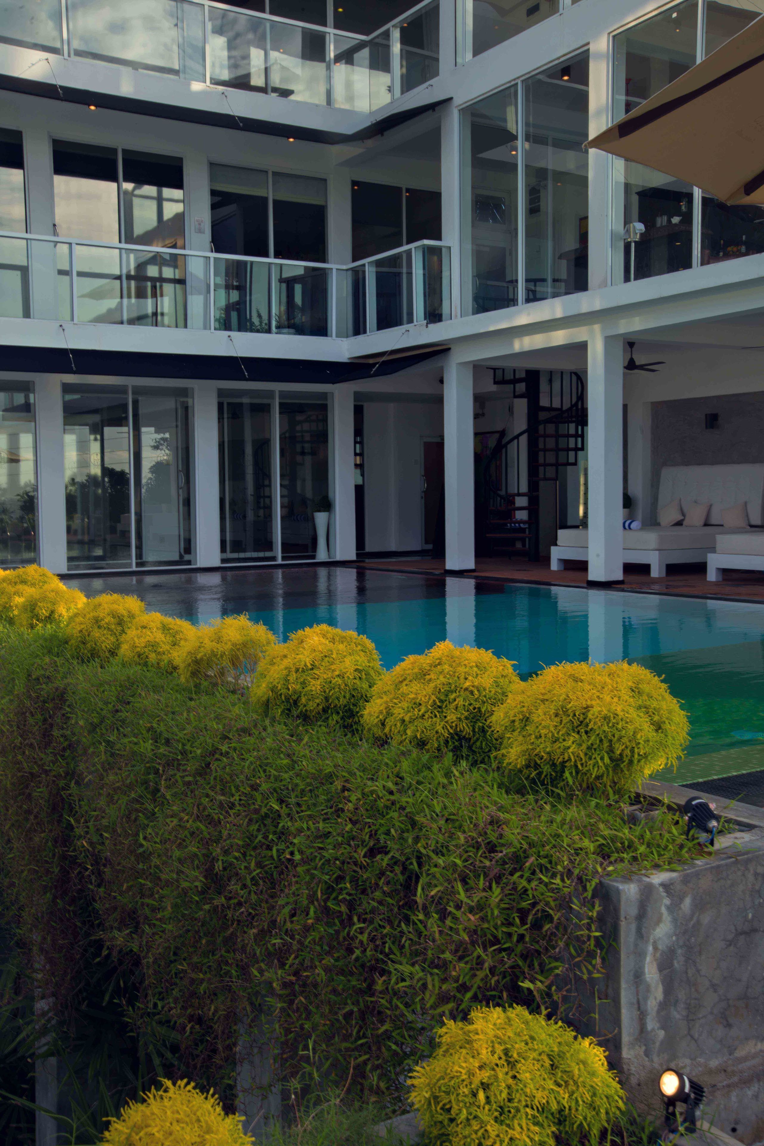 A modern multi-level house with a swimming pool, glass railings, and a staircase.