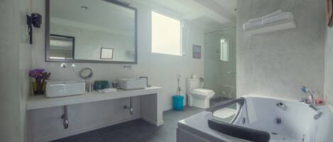 A modern bathroom with a large mirror, dual sinks, a bathtub, and a toilet.