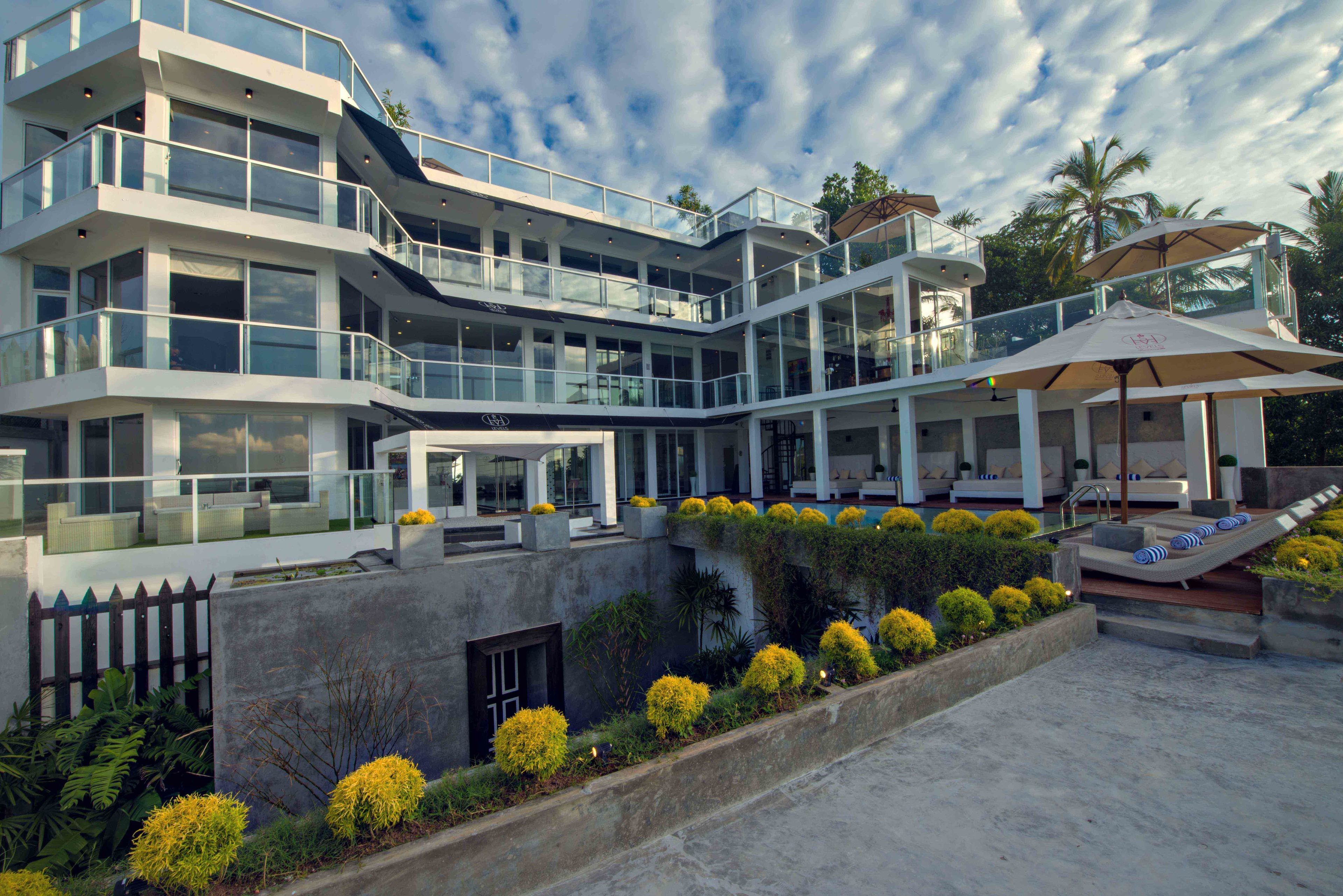 A multi-story hotel with a pool area, outdoor seating, and a landscaped garden.