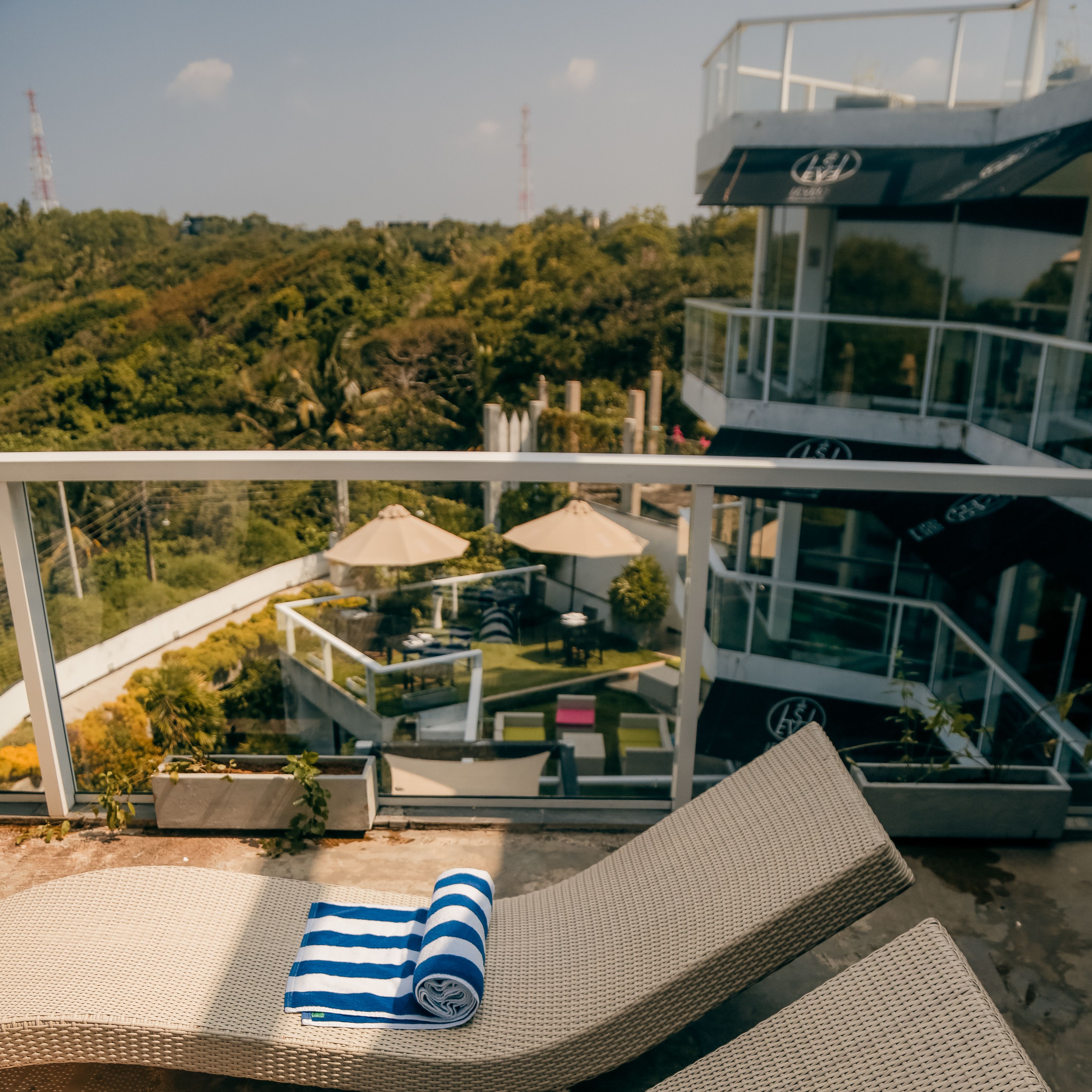 A modern outdoor lounge area with wicker lounge chairs and a blue-striped towel.