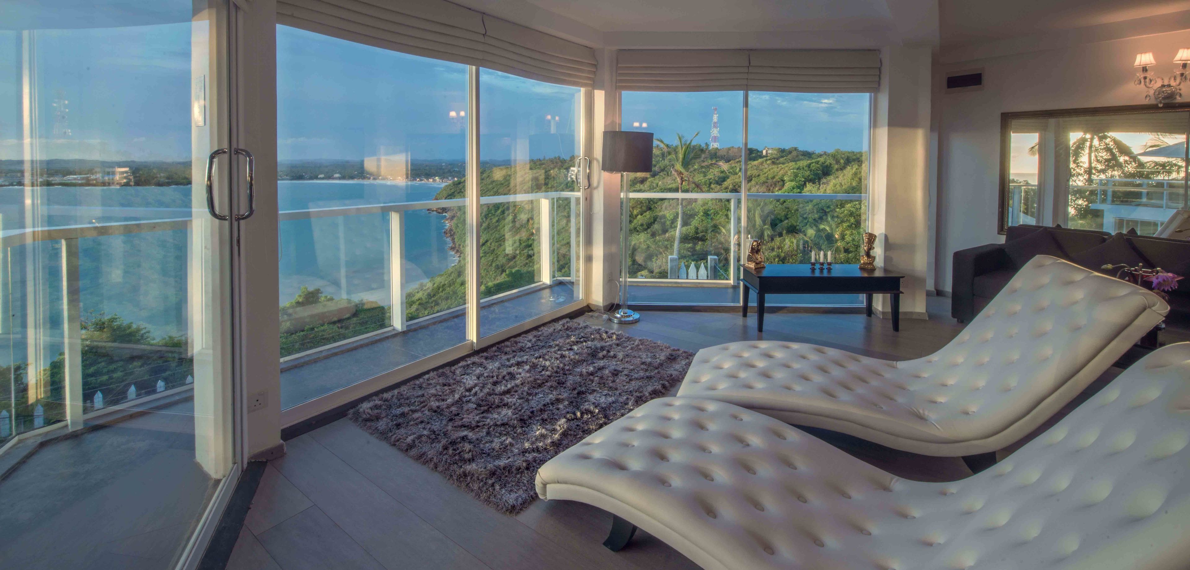 A modern living room with a large glass balcony overlooking a scenic view.