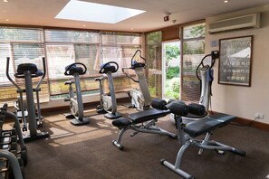A gym with exercise equipment, large windows, and a ceiling fan.
