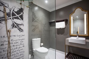 A modern bathroom with a glass shower enclosure, a white toilet, and a vanity with a mirror.