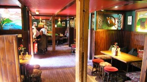 A restaurant interior with wooden floors, booths, and a bar area. - Moulin Hotel (Pitlochry)
