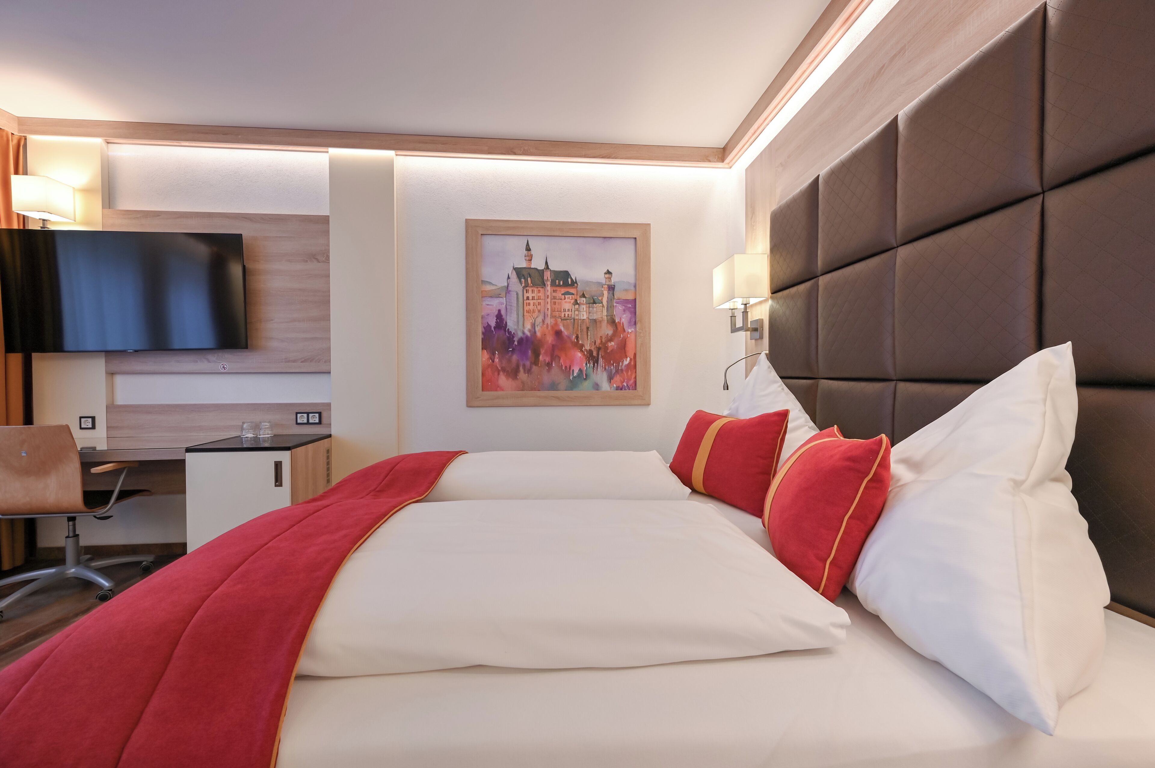 Una habitación de hotel con una cama grande, un escritorio, una silla, un televisor de pantalla plana y un cuadro en la pared.