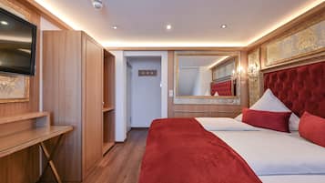 Een hotelkamer met een groot bed, een televisie, houten meubels en een spiegel.