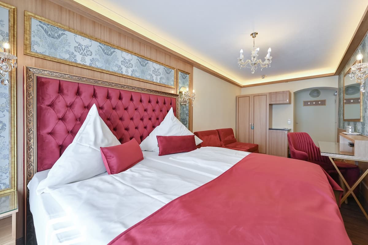 A large bed with a tufted headboard, a desk with a chair, and a mirror.