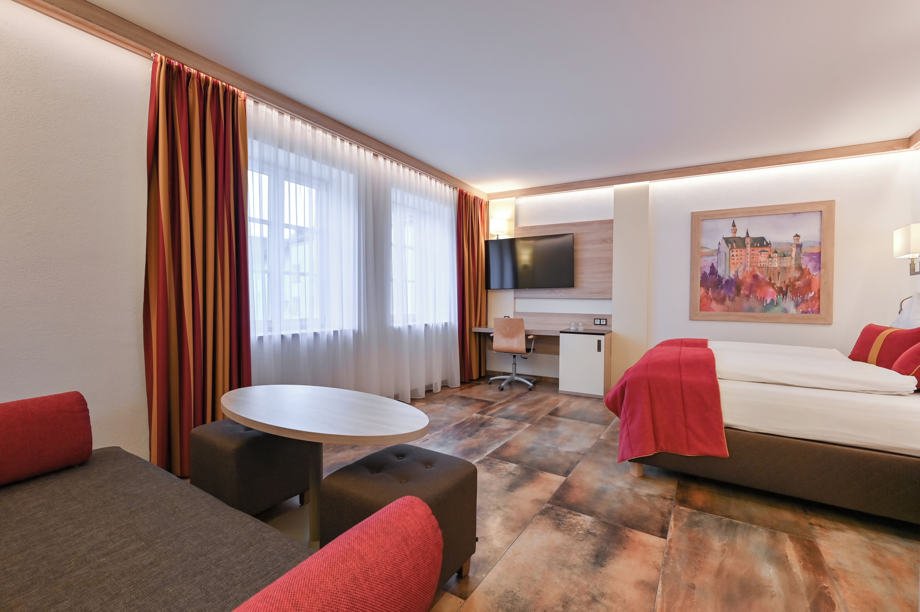 A hotel room with a bed, a desk, a TV, and a painting.