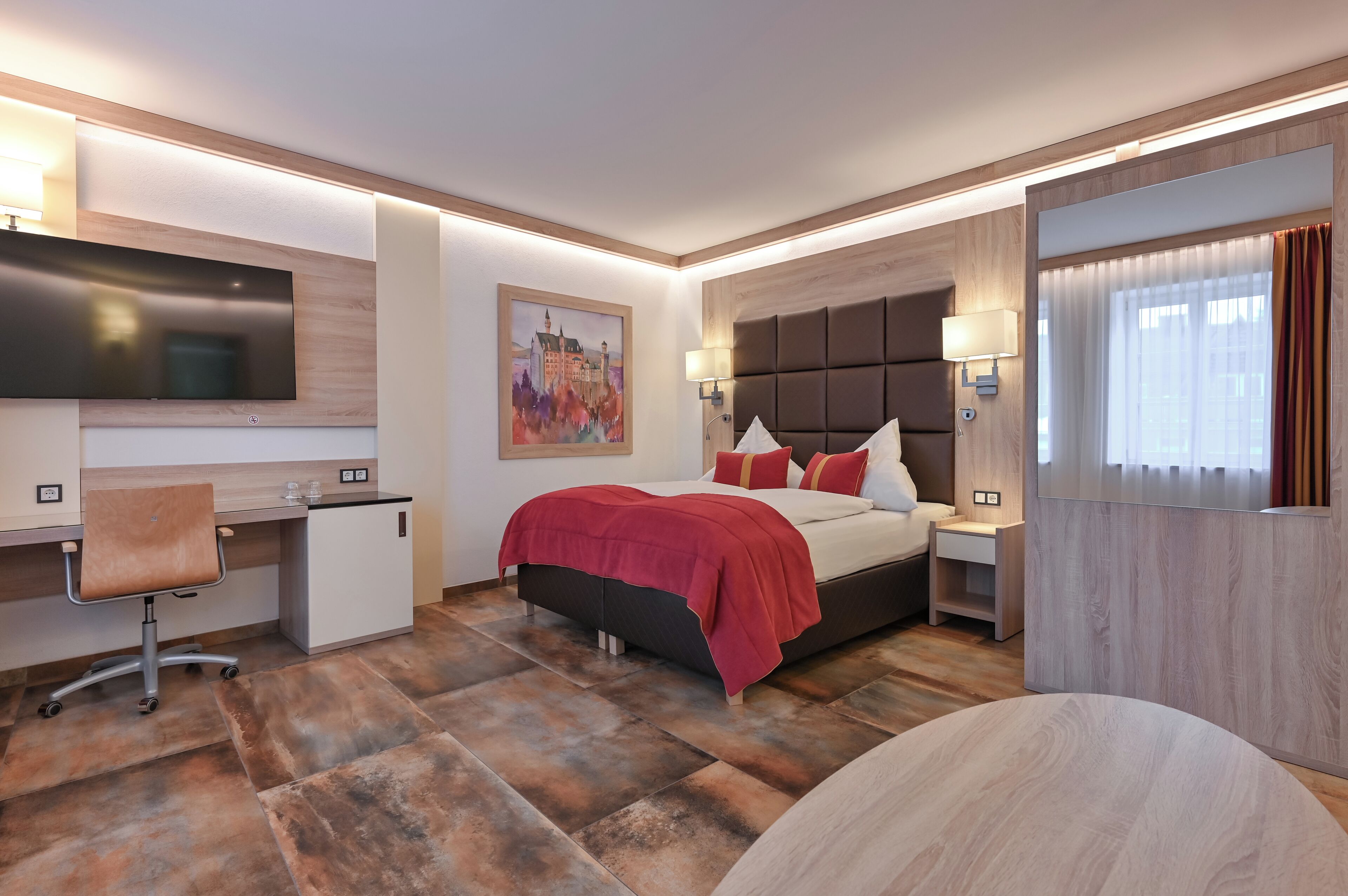 Ein modernes Hotelzimmer mit Bett, Schreibtisch, Stuhl, Fernseher und Kunstwerken.