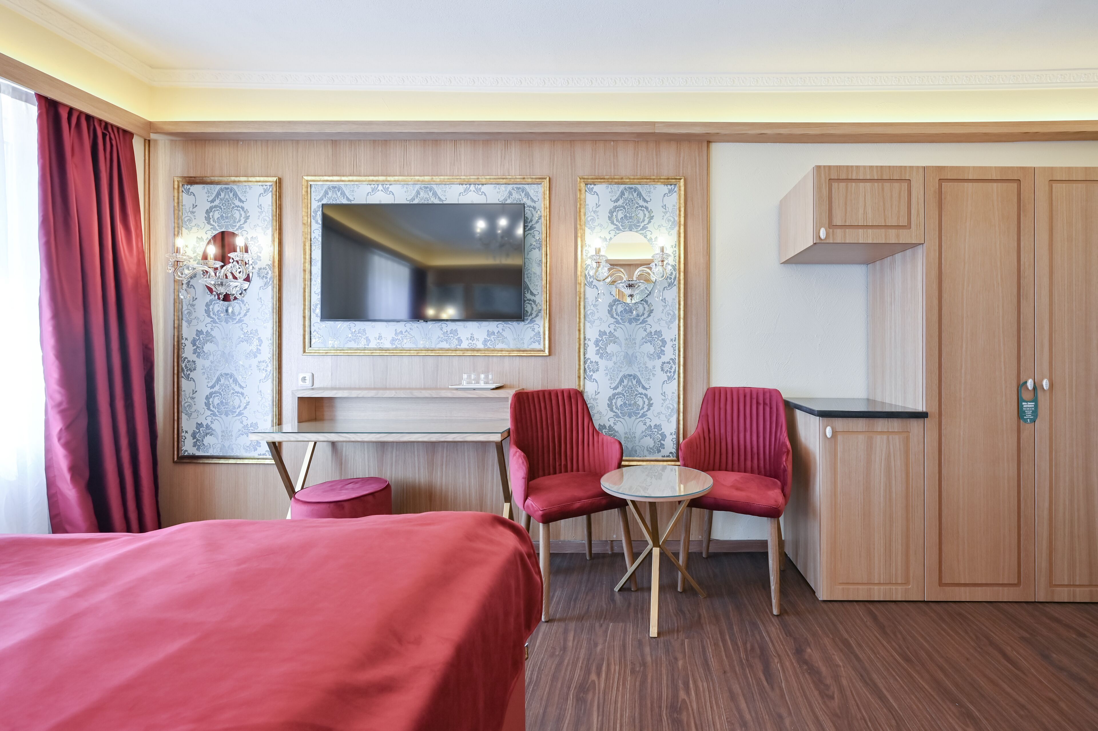 Een hotelkamer met een bed, een bureau met twee stoelen, een televisie en een kledingkast.