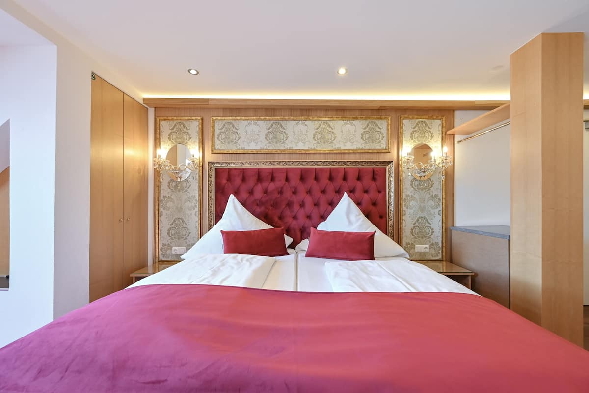A double bed with a red headboard, white bedding, and two red pillows.
