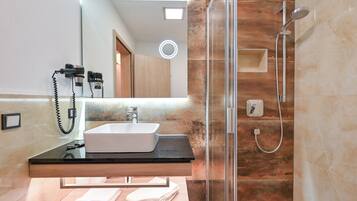 Une salle de bain moderne avec une douche à l’italienne en verre, un plan de toilette noir et un lavabo blanc.
