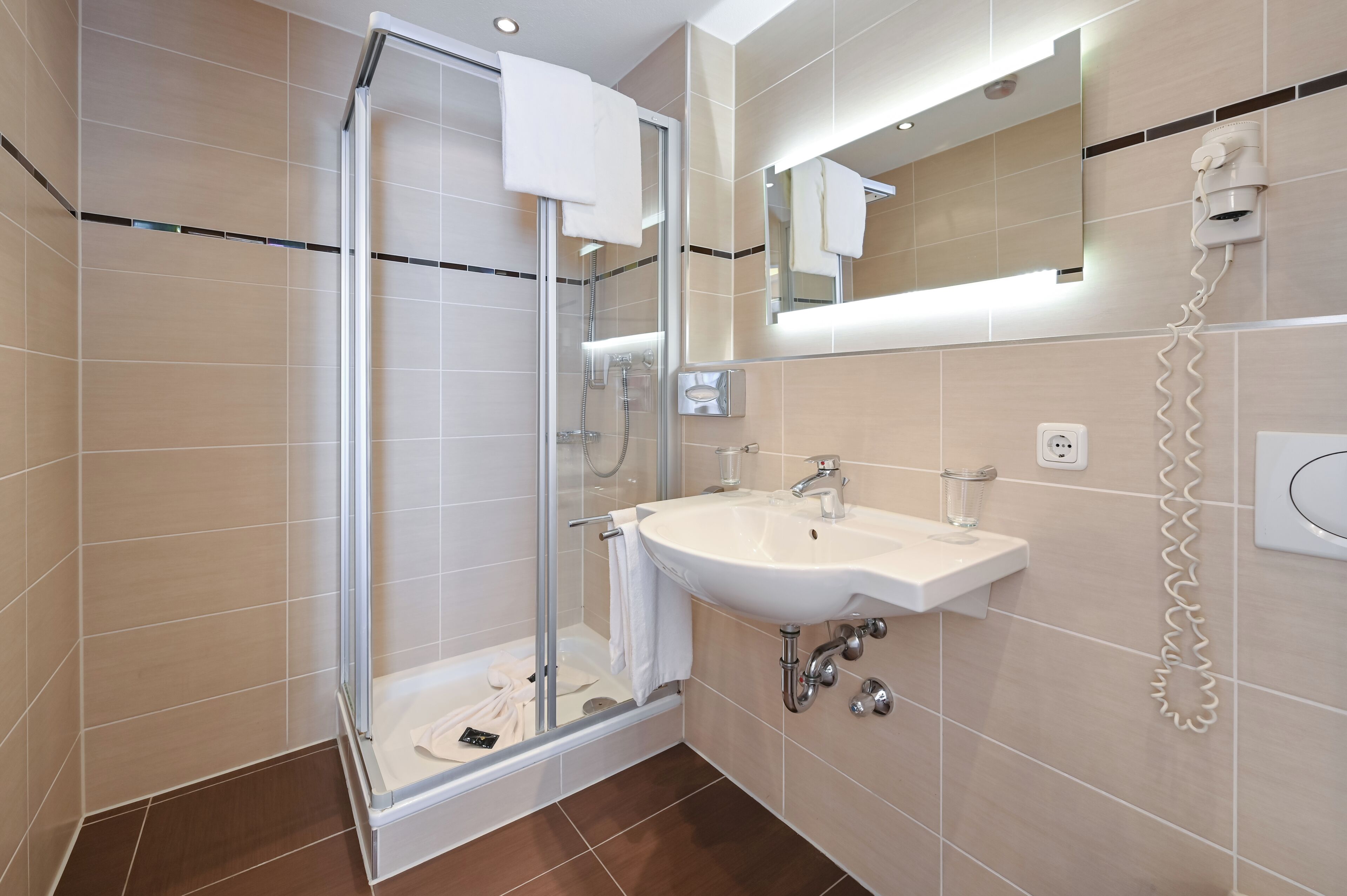 A modern bathroom with a glass-enclosed shower, a sink, and a mirror.