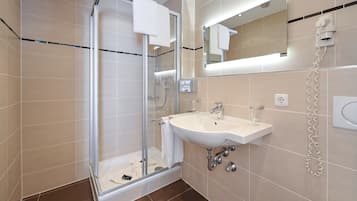A modern bathroom with a glass-enclosed shower, a sink, and a mirror.