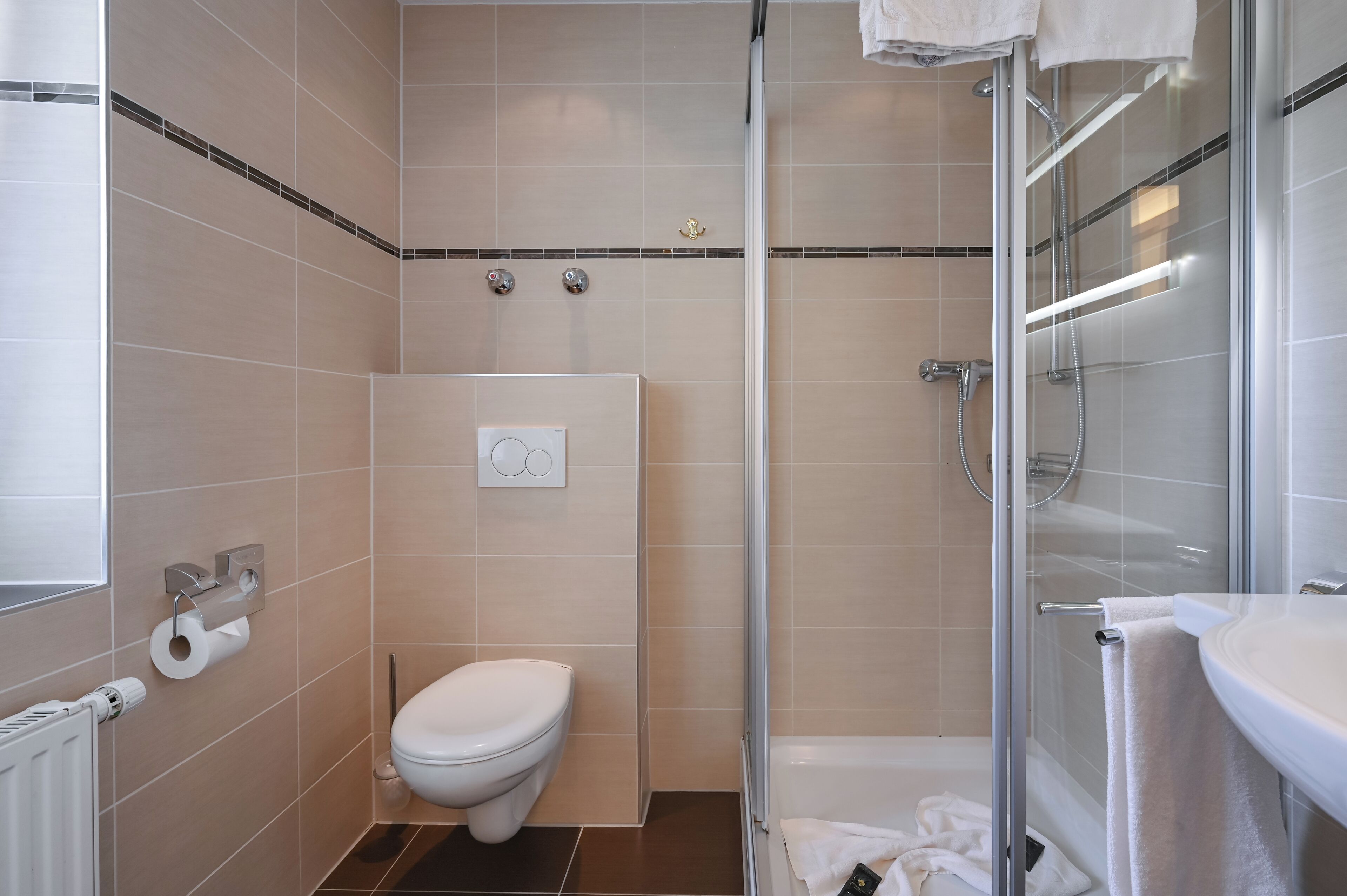 A modern bathroom with a toilet, a shower, and a sink.