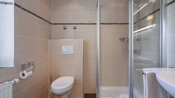 A modern bathroom with a toilet, a shower, and a sink.