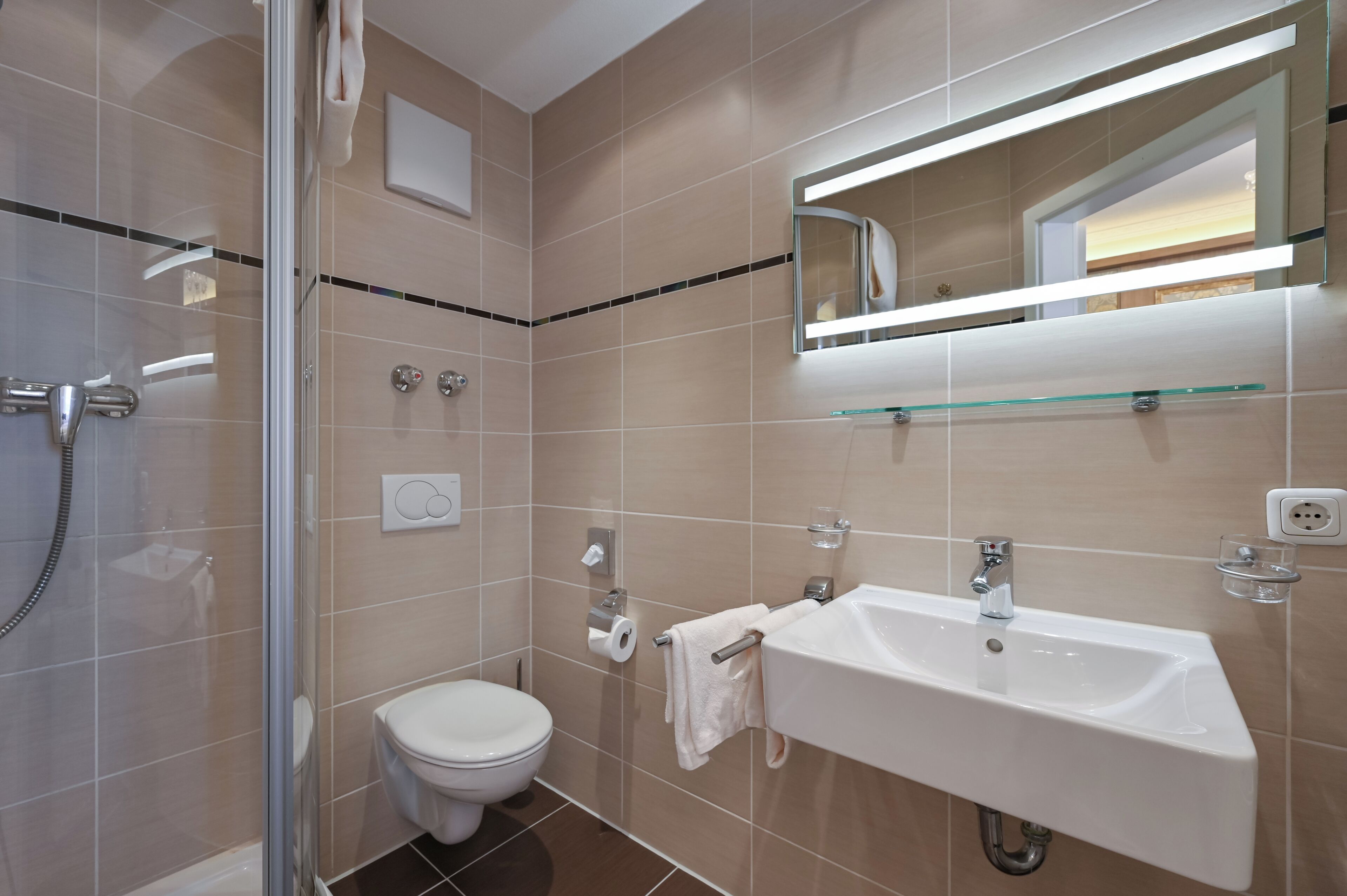 Ein modernes Badezimmer mit Duschkabine aus Glas, Waschbecken in Weiß und Toilette.