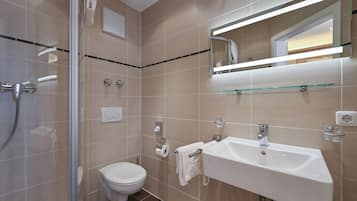 Ein modernes Badezimmer mit Duschkabine aus Glas, Waschbecken in Weiß und Toilette.