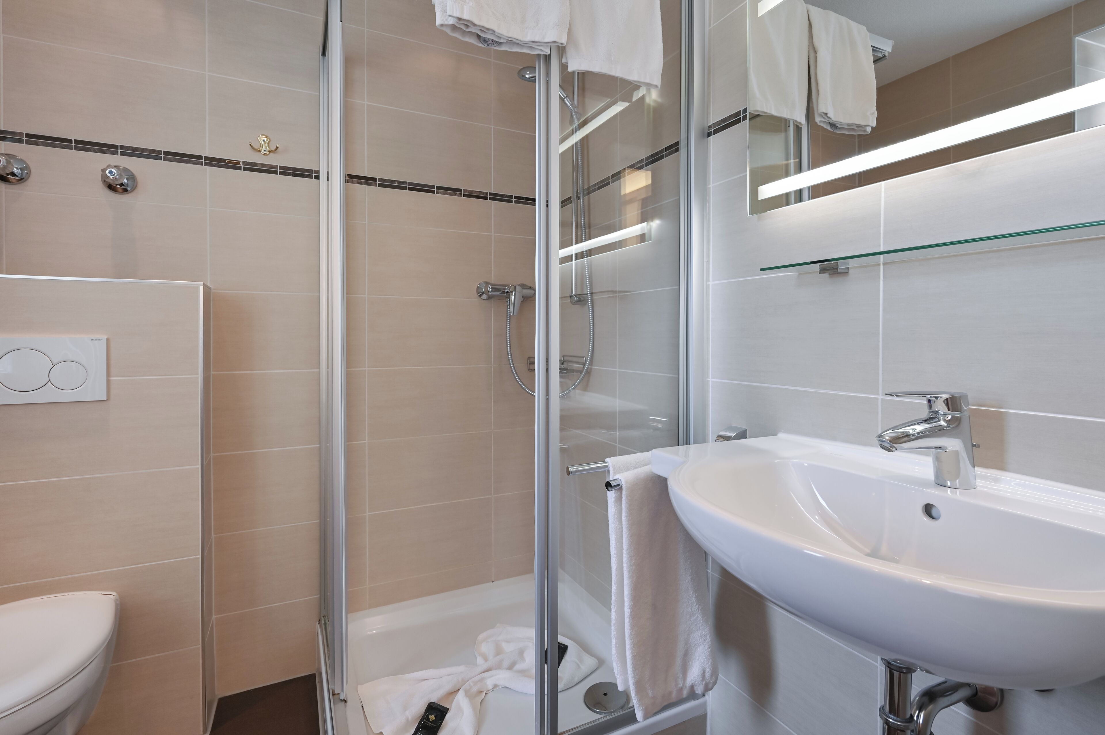 Un baño moderno con cabina de ducha de vidrio, un lavabo blanco y un inodoro.
