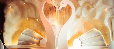 A modern interior with a heart-shaped light fixture, seating areas, and a textured wall.