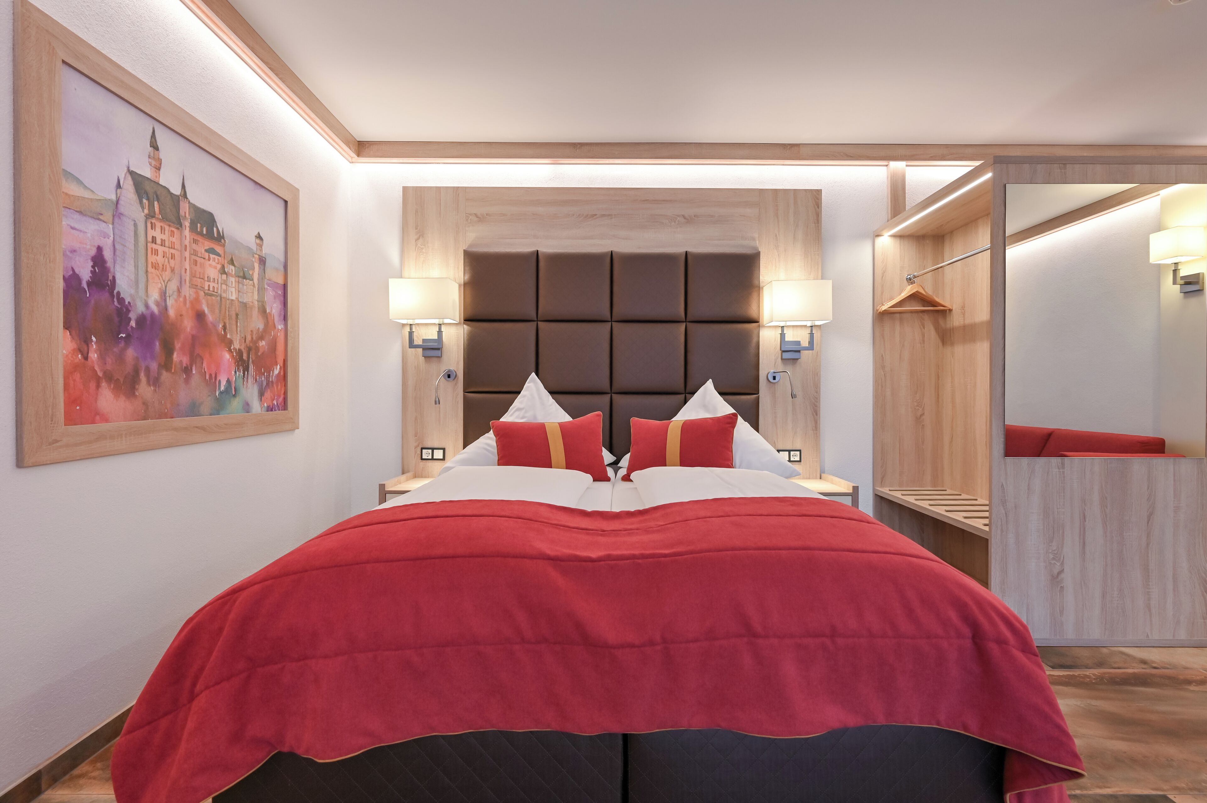 Une chambre d’hôtel moderne avec un grand lit, une tête de lit au design élégant et rembourrée, des lampes de chevet et un tableau au mur.