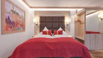 A modern hotel room with a large bed, a headboard with a padded design, bedside lamps, and a painting on the wall.