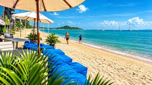 A beach with lounge chairs and umbrellas, a clear sky, and sailboats in the distance. - Roz Marine Boutique HOTEL (Koh Samui)