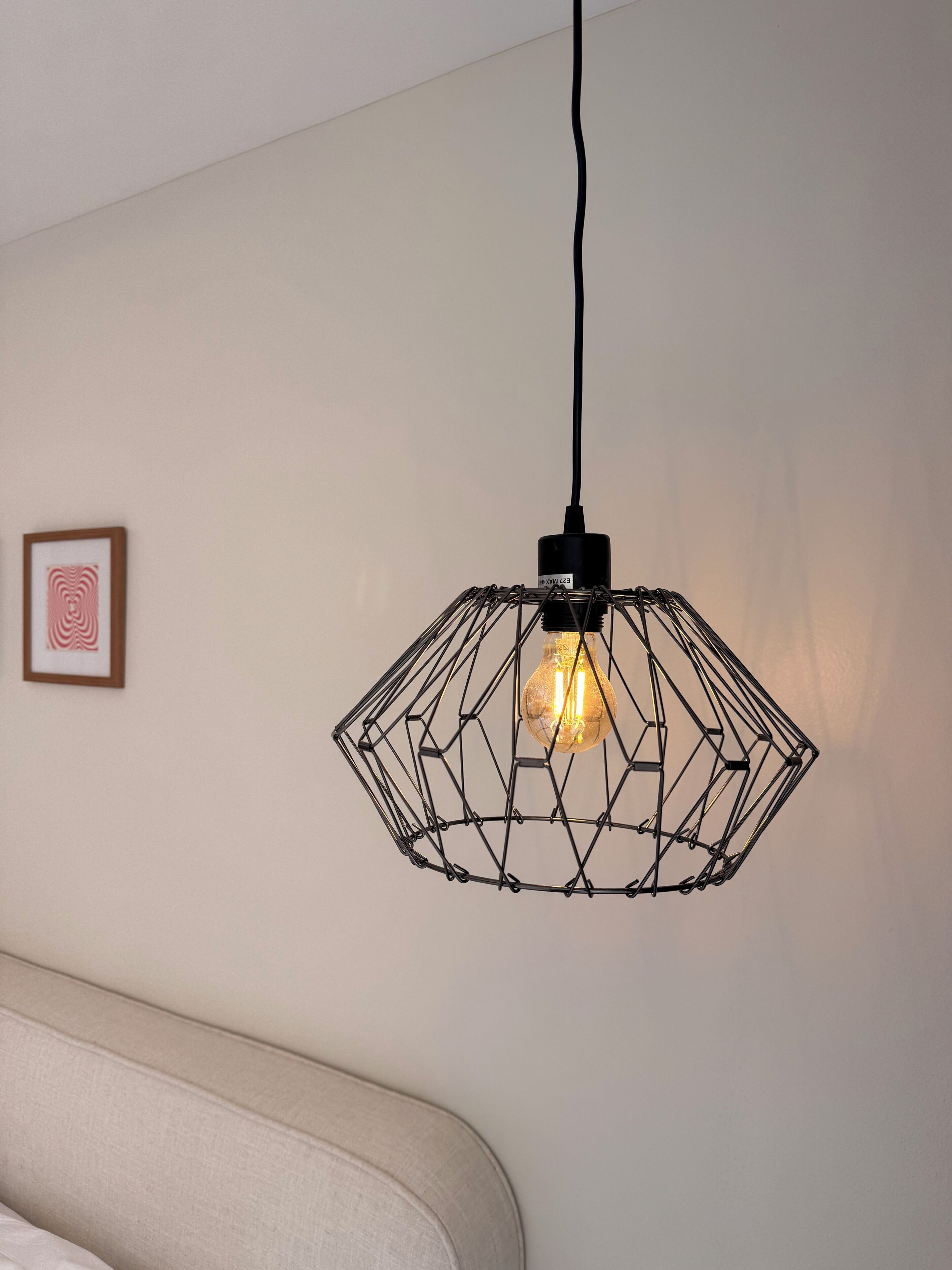 Eine geometrische Pendelleuchte mit sichtbarem Stromkabel, die von der Decke hängt.