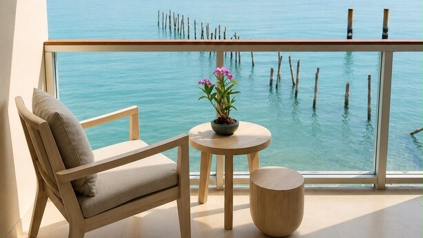A balcony with a view of the sea, a wooden chair, a small round table, and a potted plant. - Roz Marine Boutique HOTEL (Koh Samui)