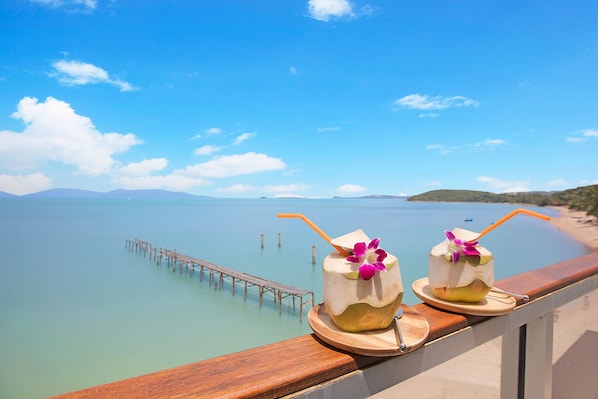 Two drinks on a wooden tray with a view of a beach and a pier. - Enjoy Beach Hotel (Koh Samui)