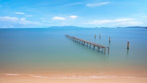 A beach with a wooden pier extending into calm waters, surrounded by clear skies. - Roz Marine Boutique HOTEL (Koh Samui)