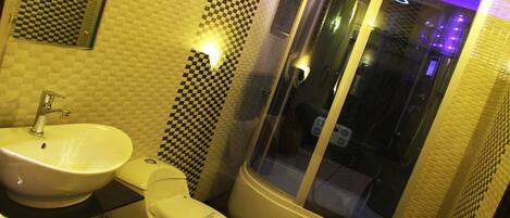 Une salle de bain équipée d’un lavabo, de toilettes et d’une douche à parois de verre.