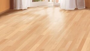 Ein Zimmer mit Holzboden, weißen Vorhängen und Blick durch eine Tür.