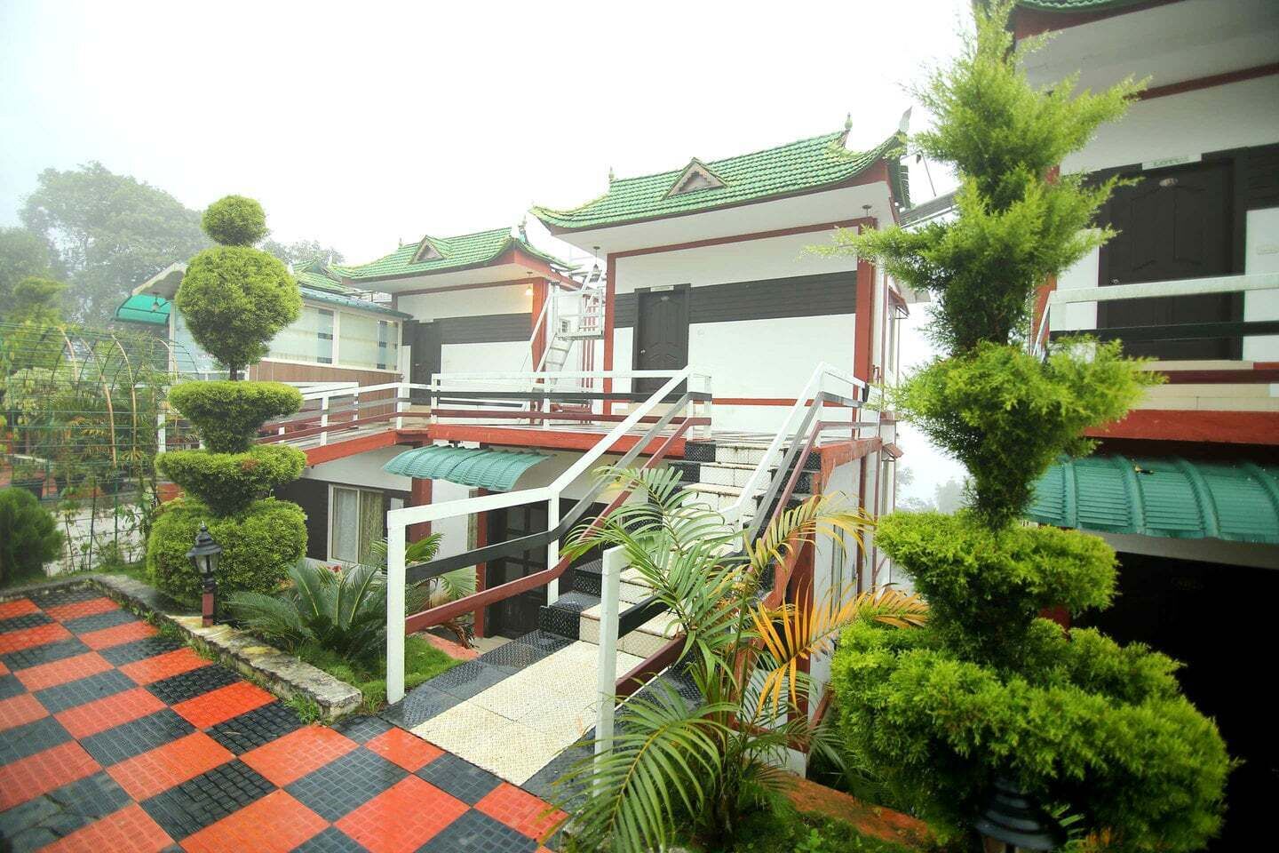A traditional-style building with a red and white exterior, a green roof, and a red and black checkered floor.