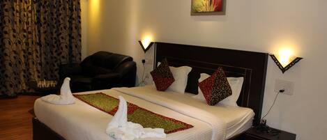 A hotel room with a large bed, two bedside tables, a chair, and a painting on the wall.