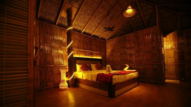 Ein Zimmer mit Holzboden, einem Bett, einer gewobenen Lampe und einem Deckenventilator.