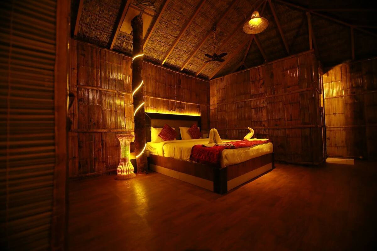 Una habitación de madera con una cama, una lámpara tejida y un ventilador de techo.