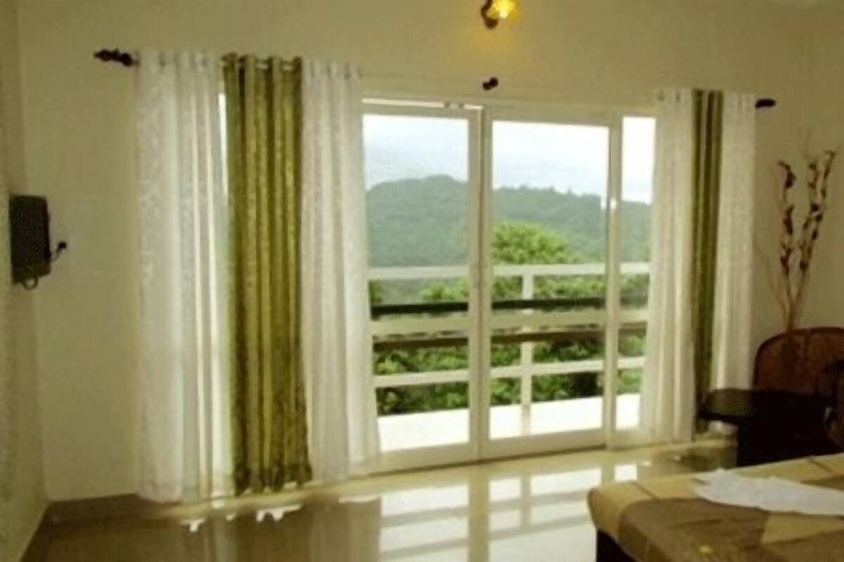 Una habitación con un amplio ventanal corredera que da a un balcón, una cama con una toalla blanca y una silla.