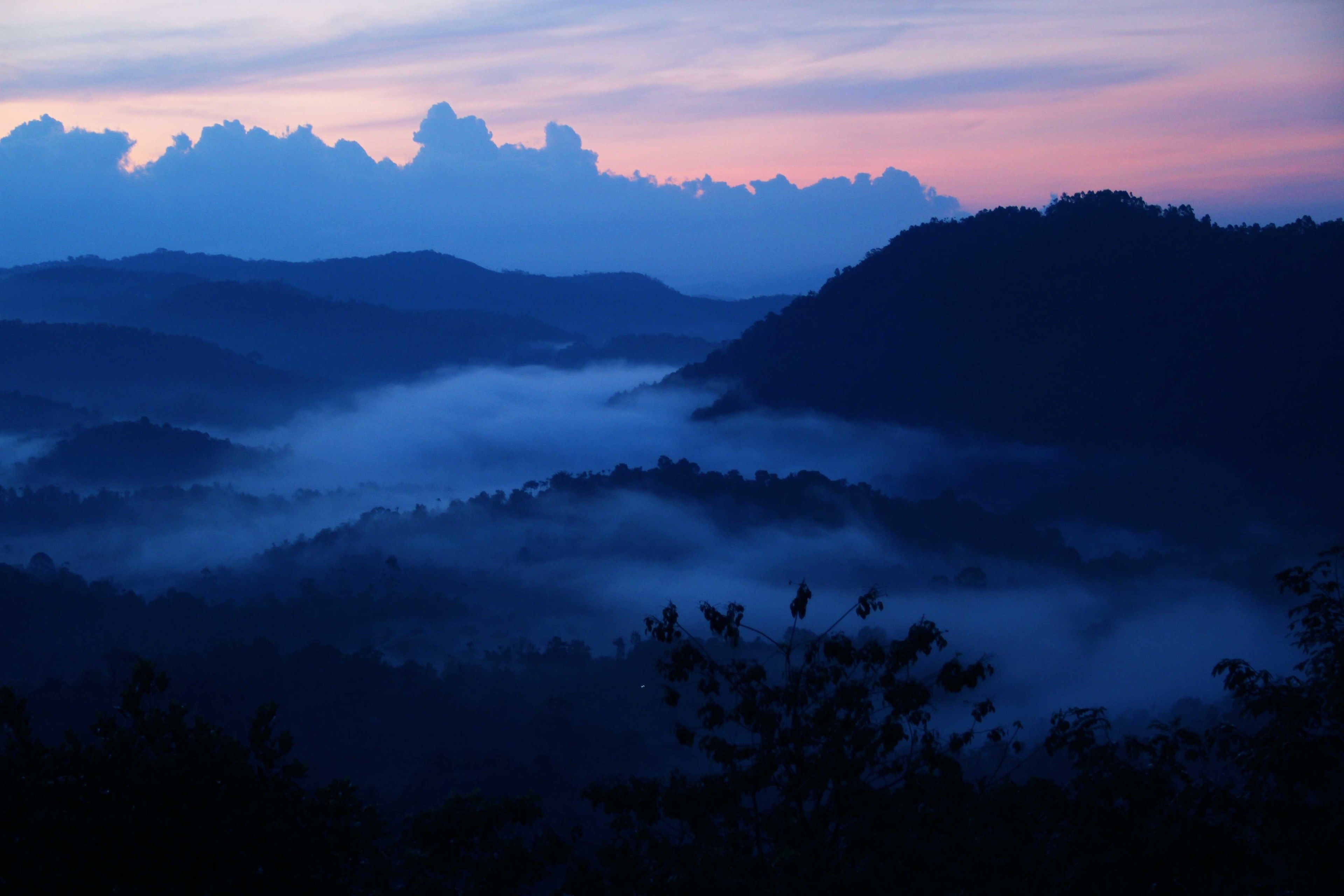 A mountainous landscape with rolling hills and a valley shrouded in mist.